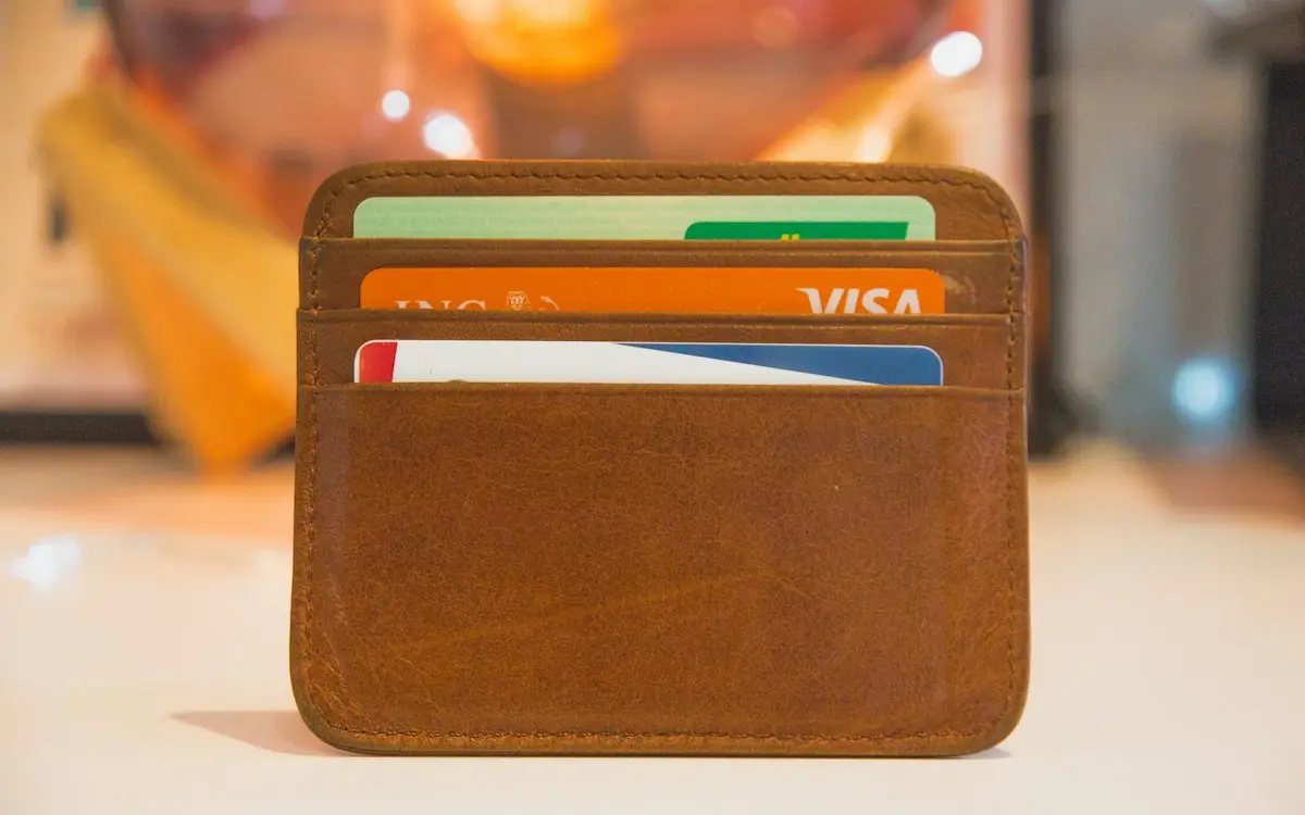 A brown leather card wallet holding several bank cards, including an orange ING Visa card